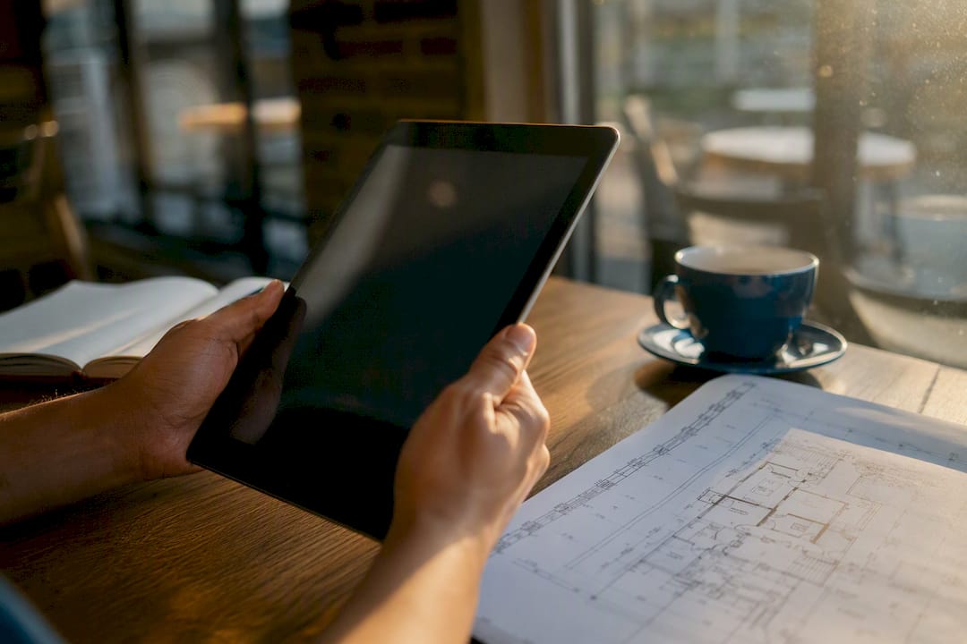 Hands holding tablet near engineering helmet